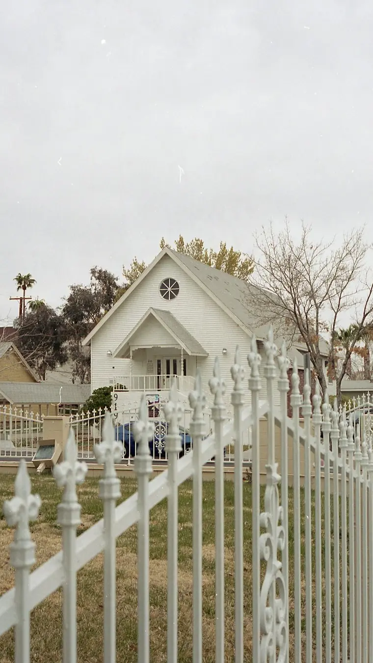 A small white clapboard wedding chapel in Las Vegas behind a white iron fence